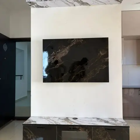 Floating TV console wall in bookmatched grey-and-white marble slab cladding with a dark marble-fronted floating storage unit below