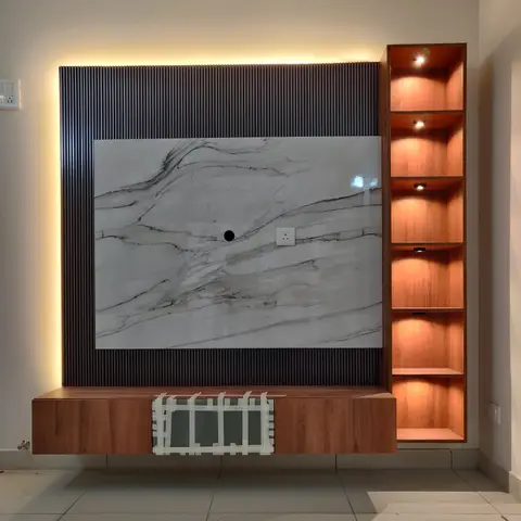 Floating wood TV console below a marble slab backdrop framed by fluted wood panelling, beside a tall backlit open shelving unit.