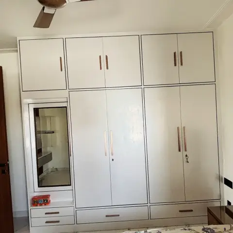 Floor-to-ceiling ivory wardrobe with loft shutters, thin black shadow-line edges and rose-gold bar handles