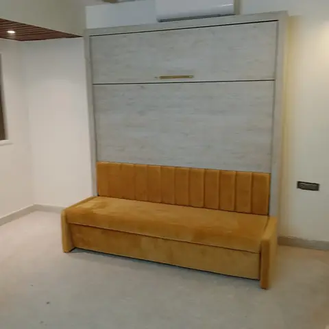 Fold-down wall bed unit with a mustard velvet channel-tufted sofa front, shown closed in an otherwise empty room.