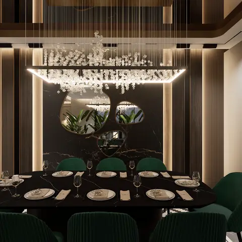 Formal dining room with a black marble table, emerald velvet chairs, and an oversized cluster chandelier against an organic-mirrored black stone wall.