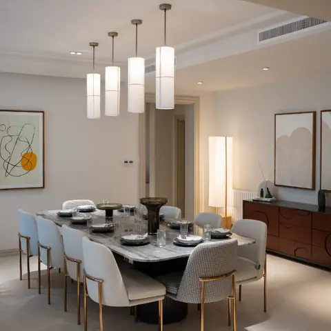 Formal dining room with a marble-top table, mixed cream and houndstooth chairs, four cylindrical pendant lights