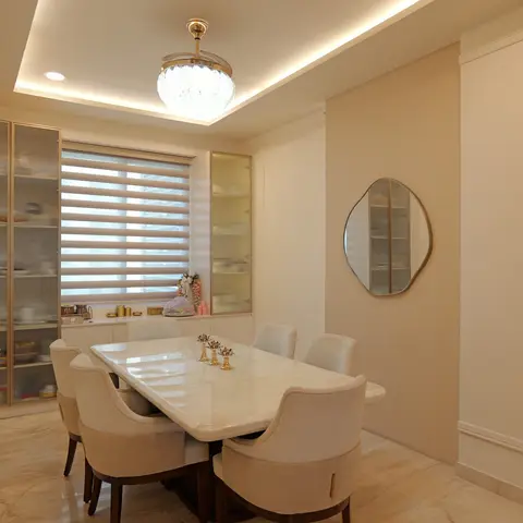 Formal dining room with a marble-top table and cream upholstered chairs beneath a crystal ceiling light