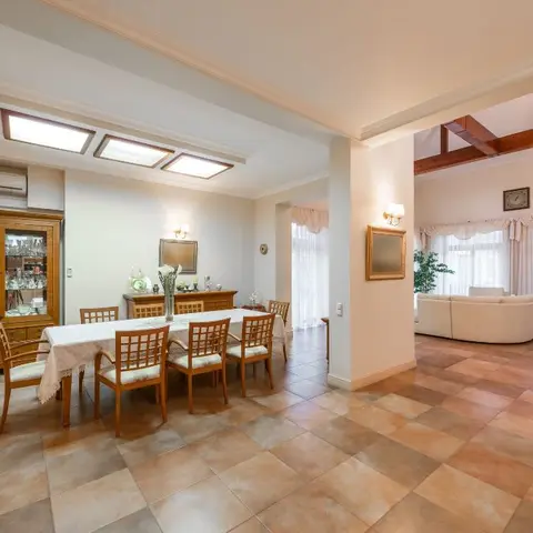 Formal dining room with a wood table and eight cane-back chairs beside a glass-front wood crockery cabinet, diamond-pattern tile floor