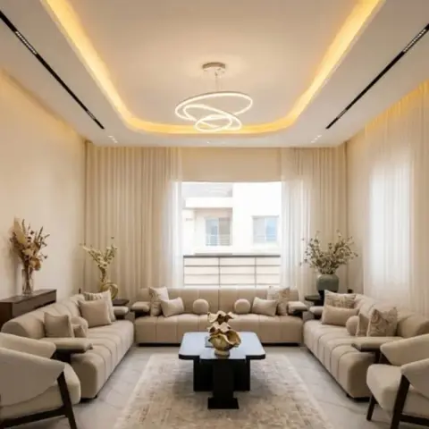 Formal drawing room with beige seating ranged along three walls under a rounded cove-lit ceiling drop