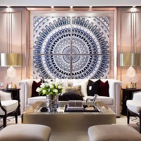 Formal living room with a large circular mandala wall-art panel flanked by pendant lamps, wingback chairs and a mirrored coffee table