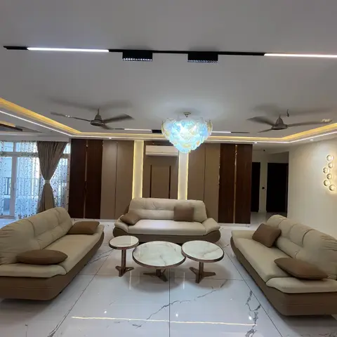 Formal living room with three cream leather sofas around round marble coffee tables beneath a scalloped statement chandelier