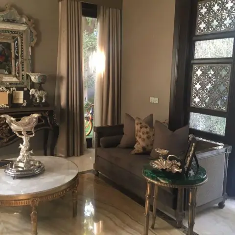 Formal sitting area near the entrance with a mirrored console styled with silver and gilt objets, a round marble-top coffee table