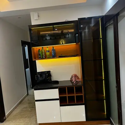 Foyer bar/display unit with black glass-shutter cabinets, backlit wine-bottle cubbies and white gloss drawers below a black granite counter.