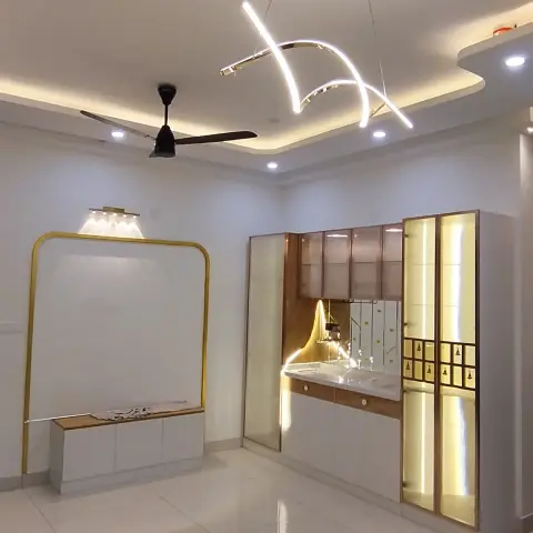 Foyer with a backlit glass-door pooja unit featuring a laser-cut bell motif panel, a sculptural arc pendant light