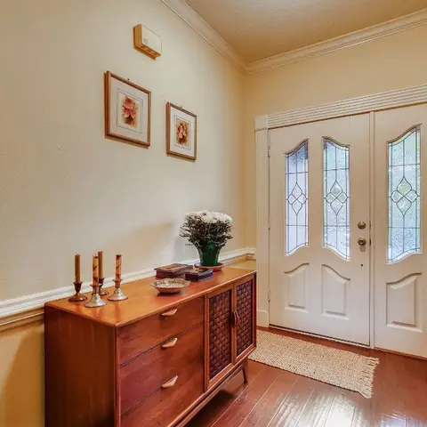 Foyer with a double leaded-glass front door, a wood console dresser styled with candlesticks and fresh flowers, and a jute entry rug.