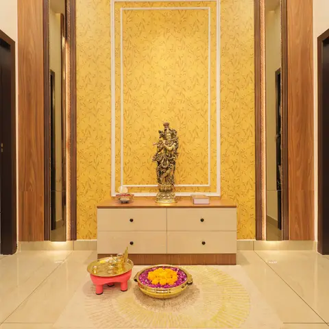 Foyer with a gold floral wallpaper feature wall framed by white moulding, a beige console table displaying a brass Krishna statue