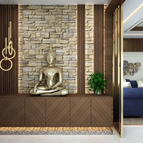 Foyer with a gold seated Buddha on a wall-hung chevron-veneer shoe console, backed by grazed split-face stone between backlit walnut fluted panels and a pebble