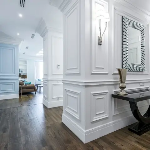 Foyer with full-height white raised-panel wall moulding, a sculptural black console table under a mirrored-frame mirror