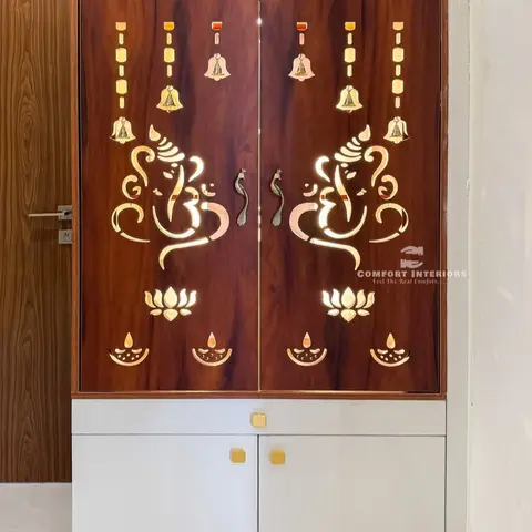 Free-standing pooja unit with backlit laser-cut Ganesha and lotus motifs on rosewood-finish doors, gold finials on top and a white storage cabinet below.