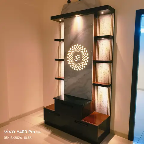 Freestanding pooja unit with a backlit marble-look panel featuring an illuminated Om jaali cutout, flanked by amber-lit onyx-look display shelves.