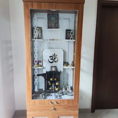 Freestanding teak-laminate mandir with a stepped temple-shaped pelmet, its glass shutters etched with Om and a Kannada Gayatri line