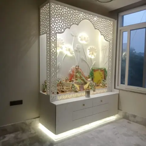 Freestanding white pooja mandir with CNC floral jaali sides, a carved lotus-relief backdrop lit from behind