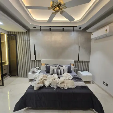 Freshly handed-over bedroom with a white upholstered headboard against a fluted grey panel wall under a textured concrete-effect panel
