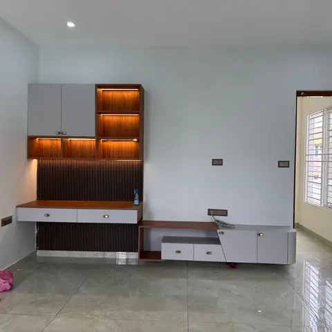 Freshly installed living-room media wall with a cove-lit open-shelf display unit and a fluted wood panel above a floating TV console.