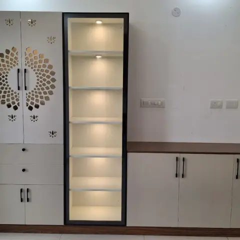 Freshly installed mandir unit against a bare wall: CNC lotus-and-sunburst cut shutters over drawers and a base cupboard
