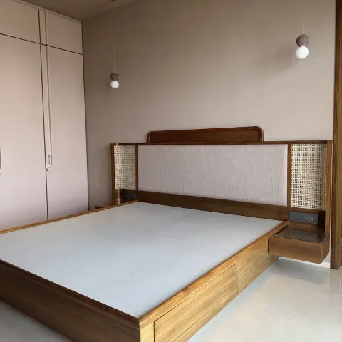 Freshly installed teak platform bed with cane-webbed flanking panels and a linen headboard, cantilevered side tables with sockets built in