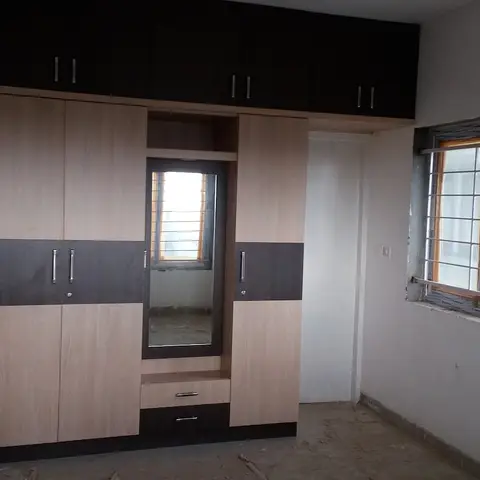 Freshly installed two-tone light-oak and dark-wenge floor-to-ceiling wardrobe with a mirrored dressing recess