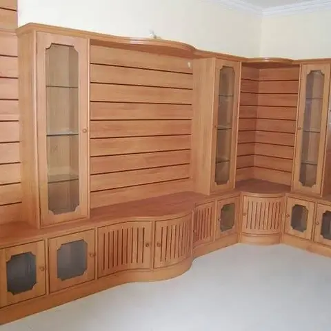 Full-wall carved wood showcase unit with fluted pilasters, multiple glass-front display cabinets, and a scalloped lower storage cabinet.