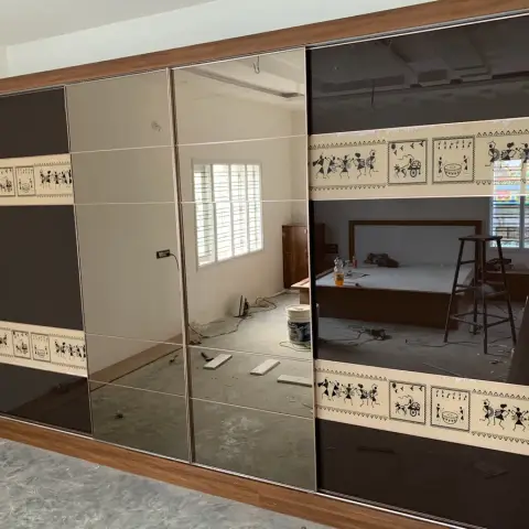 Full-wall four-shutter sliding wardrobe in bronze mirror and dark lacquered glass banded with printed Warli figures