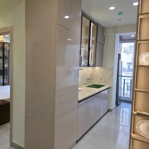Galley kitchen with glossy taupe tall units, a marble-slab backsplash, a green under-mount sink with wall-mounted swan-neck faucet