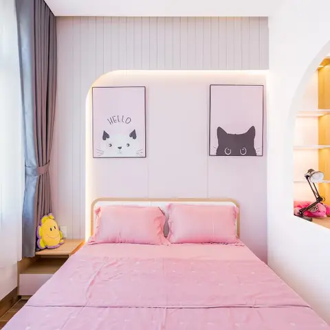 Girl's bedroom with a fluted wood-panelled headboard wall framed by twin cat-themed prints, beside an arched built-in study nook with pink-lined shelving.