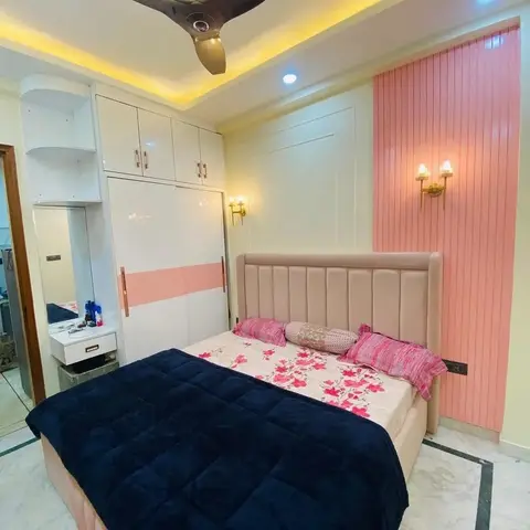 Girl's bedroom with a pink fluted panel accent wall and brass wall sconces flanking a channel-tufted headboard, a pink-and-white sliding wardrobe