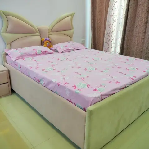 Girl's room built around a butterfly-wing headboard in cream suede with a matching two-drawer bedside