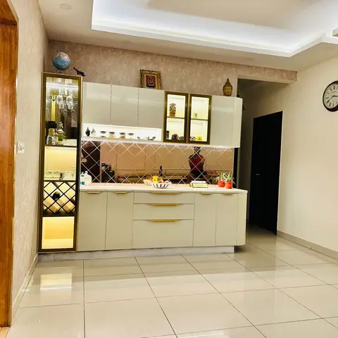 Glossy cream crockery-and-bar unit with gold-trimmed backlit glass display shelving, wine rack, and a mirrored diamond-pattern splashback