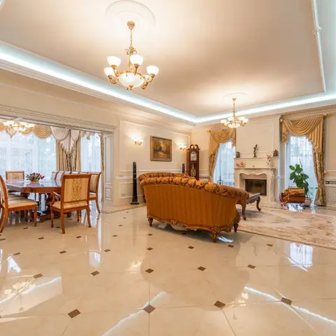 Grand cream marble-floored living room with two crystal chandeliers, a carved gilt-trim sofa facing a marble fireplace