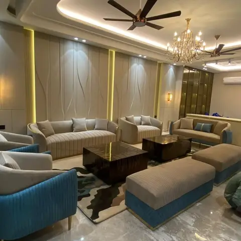 Grand living room with a curved cove-lit ceiling, twin fans and chandeliers, wave-textured gold-lit wall panels