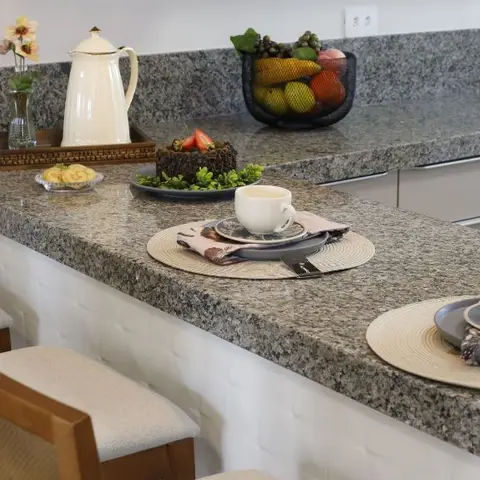Granite breakfast counter styled with a two-person place setting, fruit basket and upholstered bar stools