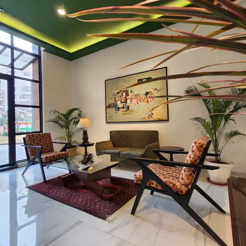 Green cove-lit ceiling living room with black angled-leg mid-century accent chairs, a glass-top wood coffee table