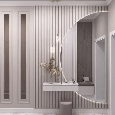 Greige fluted-panel entry wall with a large backlit circular mirror cut into it, a slim wall-hung white console holding a dried-grass arrangement