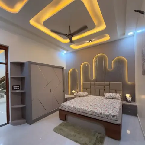 Grey bedroom where three backlit arched panels of stepped height rise behind the upholstered headboard