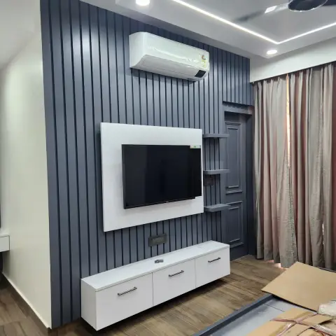 Grey fluted-panel TV feature wall with a floating white TV unit, moving boxes still stacked on the floor in front of it.