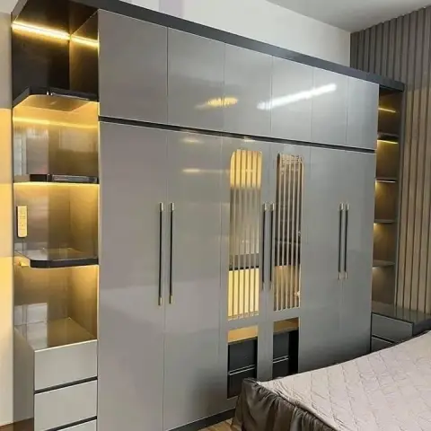 Grey high-gloss wardrobe with a full loft tier, gold-tinted fluted mirror inserts on the centre shutters and a stepped LED-lit open shelf column with drawers