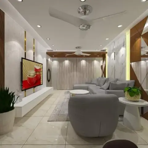 Grey L-shaped sectional and a round accent chair face a floating TV console under marble-and-wood panelled walls with brass inlay strips and a cove-lit ceiling