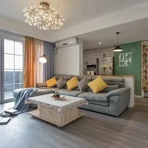 Grey L-shaped sofa with mustard and grey cushions under a cluster crystal pendant chandelier