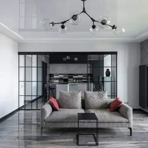 Grey living room with a tweed two-seater and a black square side table on polished grey marble