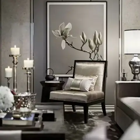 Grey-on-grey living room corner with a dark-framed champagne silk armchair set against an oversized framed magnolia painting