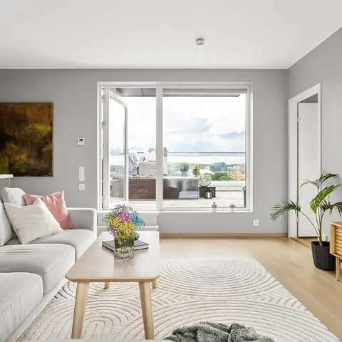 Grey Scandinavian-style living room with a wraparound sofa, wood coffee table and a fluted sideboard beside glass balcony doors