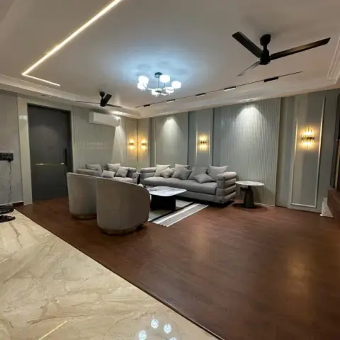 Grey sofa and two barrel swivel chairs on a raised dark-timber platform that steps down to beige marble