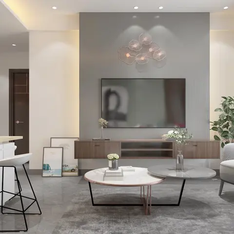 Grey TV feature wall with a metal floral wall sculpture, floating wood media console and two round nesting coffee tables in front of a grey armchair