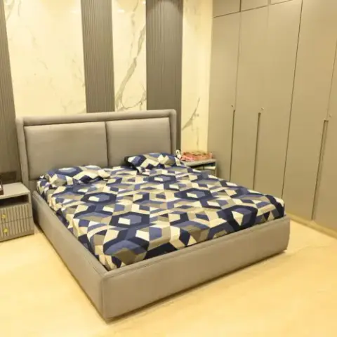 Grey upholstered bed under a marble-look headboard panel flanked by grey fluted strips